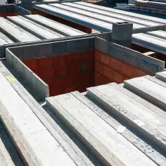 Budowa domu w toku. Betonowe belki stropowe tworzą konstrukcję stropu filigran, czekając na dalsze prace.