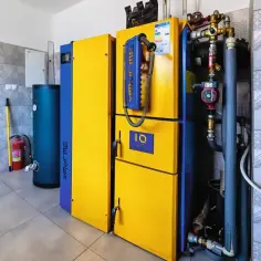 Kocioł 20kW na pellet, idealny do ogrzania domu o powierzchni do 200m². Obok zasobnik wody.