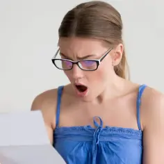 Zaskoczona kobieta w okularach czyta dokument. Czy to wypowiedzenie umowy zlecenia?