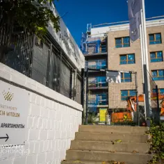 Budowa apartamentów z tablicą "Apartamenty Księcia Witolda" i koparkami.