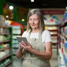 Pracownica sklepu z tabletem, planująca, ile lat przed emeryturą pracownik jest pod ochroną.
