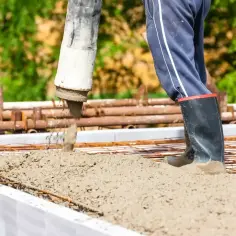 Betoniarz w gumowcach wylewa beton na zbrojenie. Różne rodzaje betonu są kluczowe dla wytrzymałości konstrukcji.