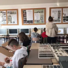 Uczniowie pracują nad projektami wnętrz w pracowni komputerowej, na ścianach wiszą wizualizacje.