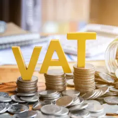 Żółte litery VAT na stosach monet, symbolizujące podatki i finanse, zgodnie z art. 113 ust. 1 ustawy o VAT.