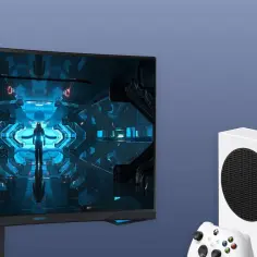 Zakrzywiony monitor gamingowy z grą, obok konsol Xbox Series X/S i kontrolera.