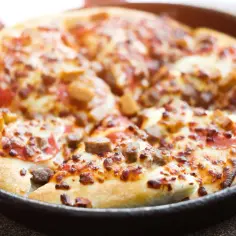 Pyszna pizza z patelni bez drożdży, z kawałkami mięsa i serem, gotowa do podania.