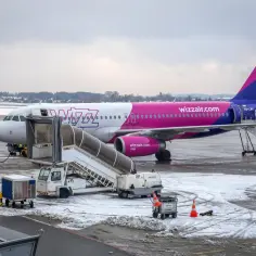 Samolot Wizz Air na lotnisku zimą. Zastanawiasz się, ile kosztuje bagaż rejestrowany Wizzair? Sprawdź ceny przed podróżą!