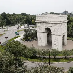 Łuk Triumfalny w Warszawie, otoczony zielenią i ruchem miejskim, przypomina o historii i architekturze miasta.