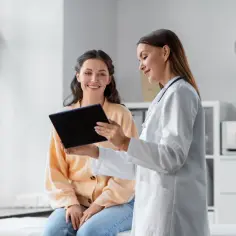 Lekarka omawia z pacjentką możliwości dofinansowania laserowej korekcji wzroku, pokazując coś na tablecie.