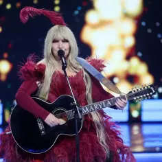 Maryla Rodowicz w pióropuszach i z gitarą, gotowa do wykonania swoich niezapomnianych utworów.