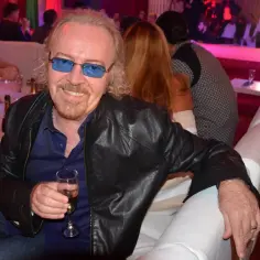 Umberto Tozzi, w okularach, z kieliszkiem szampana, jakby śpiewał "Ti amo".