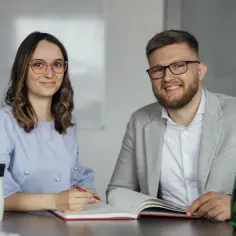 Uśmiechnięci pracownicy omawiają zatrudnienie osoby niepełnosprawnej i ulgi we wpłatach na PFRON.