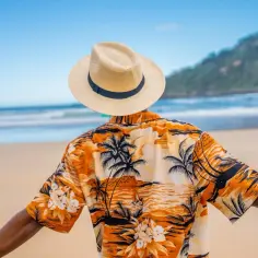 Chłopiec w hawajskiej koszuli i kapeluszu na plaży. Inspiracja, jak zrobić strój hawajski dla chłopca.