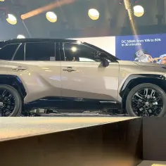 Nowa RAV4 prezentowana na scenie, z ekranem pokazującym dane ładowania.