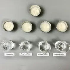 Sześć próbek kremów w małych pojemnikach i cztery zlewki z płynami: propanediol, glikol propylenowy, **butylene glycol** i pentylene glycol.