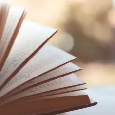 Otwarta książka z przewracanymi stronami, widoczne numery stron i tekst.