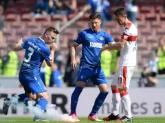 Piłkarze Karlsruher SC w niebieskich strojach, jeden z nich z numerem 3, otoczeni dymem z rac.