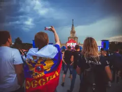 Fani w moskiewskim klubie piłkarskim, jeden z nich z flagą Rosji, nagrywa telefonem koncert.