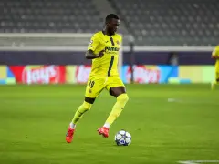 Piłkarz Villarrealu z numerem 19 na koszulce drybluje z piłką na murawie.