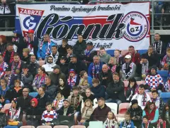 Tłum kibiców Górnika Zabrze, w szalikach i barwach klubowych, wspiera drużynę.