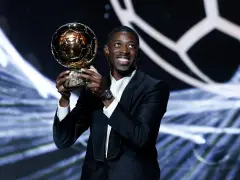 Piłkarz Ousmane Dembélé trzyma Złotą Piłkę na scenie.