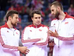 Trzech siatkarzy w strojach z biało-czerwoną flagą Polski. Jeden z nich trzyma puchar, symbolizujący, kto jest aktualnym mistrzem świata w siatkówce.