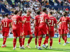 Piłkarze Liverpoolu, mistrzowie Anglii, świętują na boisku. Widać numery 11, 14, 8, 38, 21 i 2.