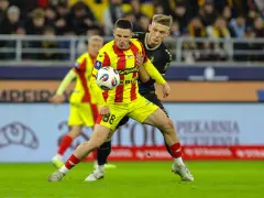 Piłkarz w żółto-czerwonej koszulce walczy o piłkę z rywalem w czarnym stroju. Intensywny przebieg: Pogoń Szczecin – Korona Kielce.