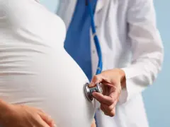 Lekarz osłuchuje brzuch ciężarnej kobiety stetoskopem. Dbałość o zdrowie w ciąży to podstawa.