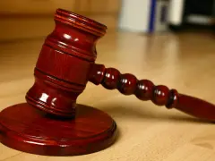 Młotek sędziowski na drewnianym stole. Symbolizuje sprzedaż mieszkania z wpisem komorniczym i decyzje prawne.