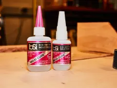 Two bottles of Bob Smith Industries Maxi-Cure glue, explaining why super glue is so strong due to its cyanoacrylate formula.