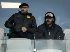 Właściciel wieczystej kraków, w czapce i okularach, siedzi obok mężczyzny w bluzie z kapturem.