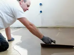 Un ouvrier applique du ragréage autonivelant sur un sol, créant une surface lisse et uniforme.