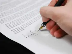 Dłoń podpisuje dokument, być może oświadczenie o odrzucenie spadku.