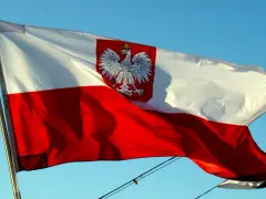 Polska bandera z orłem na tle błękitnego nieba. To symbol dumy narodowej, który powiewa na wietrze.