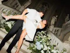 Un couple s'embrasse passionnément sur un escalier orné de fleurs, un moment clé pour réussir son mariage.