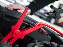 Rotes Kabel mit Krokodilklemme wird an Autobatterie angeschlossen. Plus oder Minus?