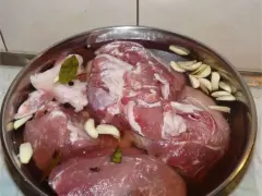 Mięso w misce z wodą, czosnkiem, zielem angielskim i liściem laurowym. To przygotowanie do wędzenia, czyli solanka do wędzenia.