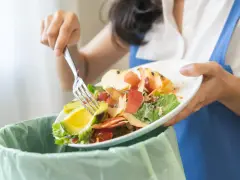 Persona separa restos de comida, como aguacate y cáscaras de manzana, para el reciclaje orgánico.