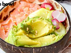 Pyszne poke bowls z łososiem, awokado, rzodkiewką i ogórkiem, posypane sezamem.