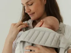 Mutter hält ihr Neugeborenes in einer Trage. Die warme Kleidung neugeborene winter schützt das Baby vor Kälte.