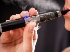 Persona usa un vaper saludable, exhalando vapor blanco.