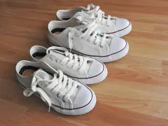 Cuatro zapatillas blancas de lona, listas para limpiar y lucir impecables.