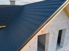 Nowy dach z ciemnogranatowej blachodachówki, wiatrownica zamontowana. Trwa obróbka dachu.
