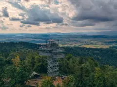 Nowoczesna trójgarb wieża widokowa góruje nad lasem, oferując zapierający dech w piersiach widok na pagórkowaty krajobraz.