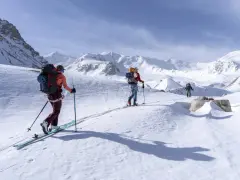 Trois skieurs s'aventurent dans un paysage montagneux enneigé. Une photo ski montagne qui capture l'immensité et la beauté de la nature.