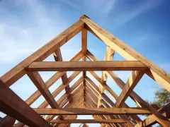 Drewniana więźba dachowa dwuspadowa tworzy geometryczny wzór na tle błękitnego nieba.