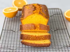 Un delicioso bizcocho de naranja, recién horneado y cortado en rebanadas, reposa sobre una rejilla.