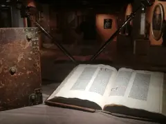 W muzeum diecezjalnym w Pelplinie eksponaty takie jak stary, oprawny księgozbiór i otwarta księga z tekstem przyciągają wzrok zwiedzających.