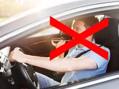 Uomo al volante che usa il cellulare, vietato dall'art. 173 CDS. La croce rossa indica il divieto.